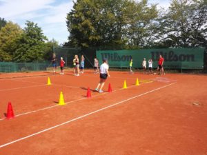 Kids spielen Spiel mit Hütchen auf dem Tennisplatz